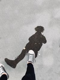 Low section of person with shadow on street