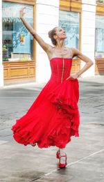 Full length of woman standing against red wall