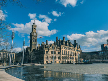 City hall by a water feature set against a blue sky 