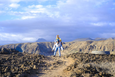 Rear view of man walking on mountain against sky