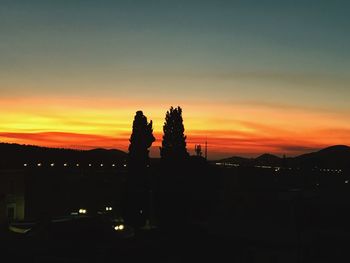 Silhouette trees against orange sky