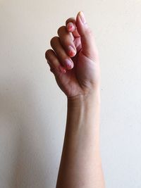 Close-up of woman hand against white wall