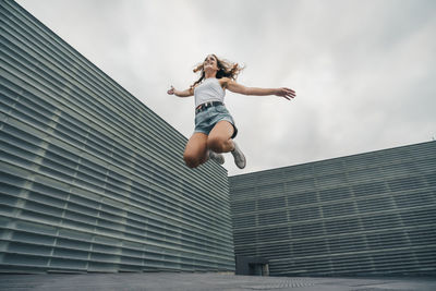 Low angle view of woman jumping against building
