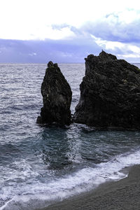 Rocks on sea shore against sky