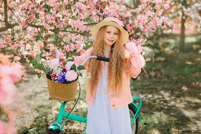 Portrait of woman with pink flower standing against plants