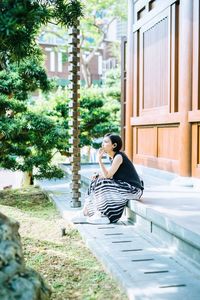 Side view of young woman sitting outdoors