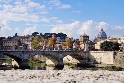 Arch bridge over river against cloudy sky