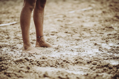 Low section of man standing on sandy beach