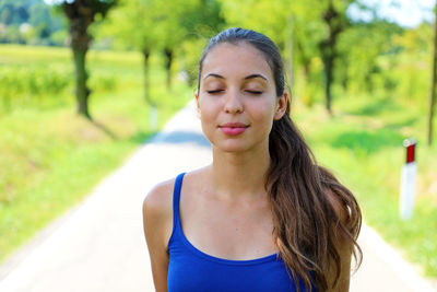 Beautiful young woman with eyes closed standing on road