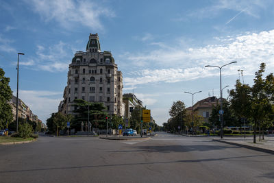 Cars on road by buildings against sky