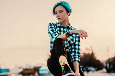 Portrait of a beautiful young woman looking away against sky during sunset