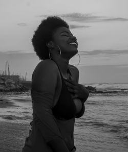 Cheerful young woman standing on beach