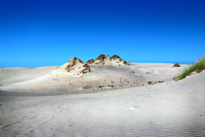 Scenic view of desert against clear blue sky