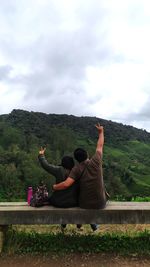 Rear view of people walking on mountain against sky