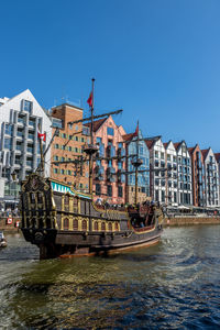 View of river by building against blue sky