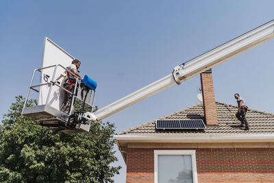 Electricians installing solar panels on house roof