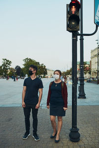 Full length of friends wearing mask standing on street in city