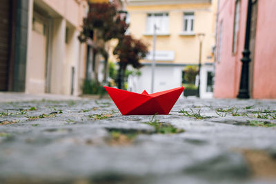 Close-up of red umbrella on street against buildings