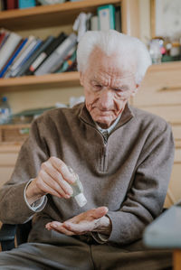 Senior man using hand sanitizer at home