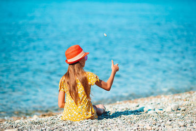 Rear view of woman sitting on beach