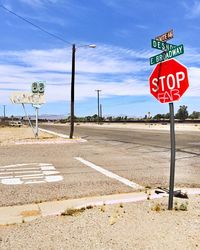 Road sign by street against sky