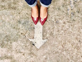 Low section of woman standing by arrow symbol on street