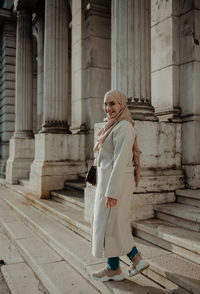 Woman standing by staircase of historic building