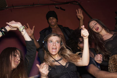 Happy young woman with arms raised at music concert