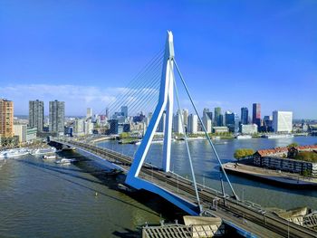 Bridge over river by buildings against sky in city