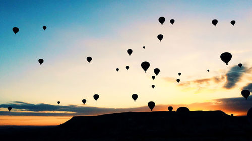 Low angle view of silhouette hot air balloons against sky during sunset