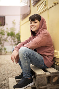 Portrait of young teen sitting against motor home while looking camera