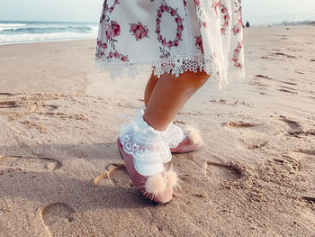 Low section of woman standing at beach