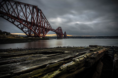 Low angle view of bridge over river against cloudy sky