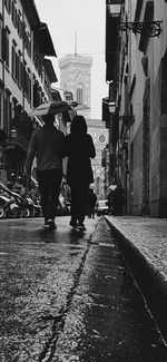 Rear view of man walking on wet street in city