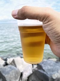Close-up of hand holding ice cream against sea