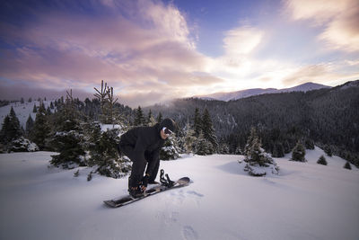 Man wearing ski on snowy mountain against sky