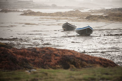 Boats moored on a beach in the rain