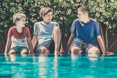 Full length of boy sitting in swimming pool