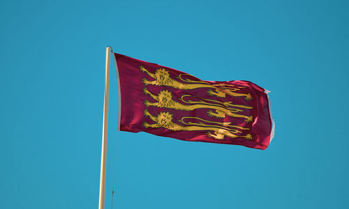 Low angle view of flag against blue sky