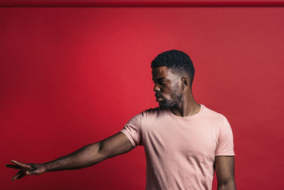 Man looking away against red wall