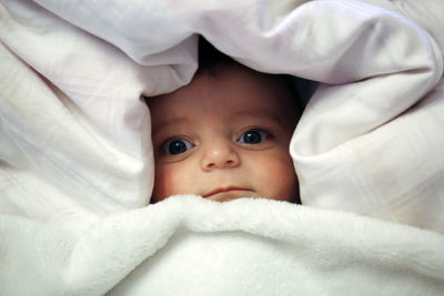 Portrait of cute baby lying on bed