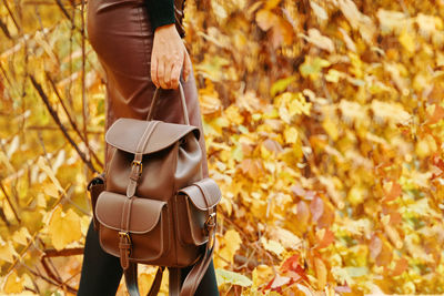 Low section of woman standing on autumn leaves