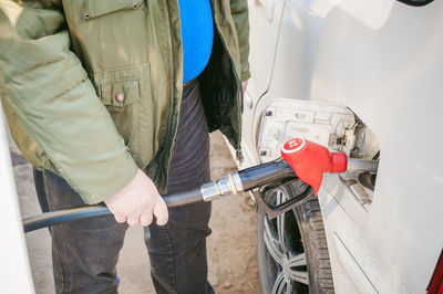 Midsection of man filling fuel in car tank