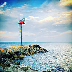 Lifeguard hut on rock by sea against sky