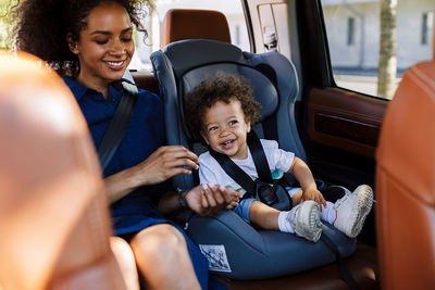 Happy mother and son sitting in car