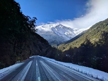 Road amidst snowcapped mountains against sky