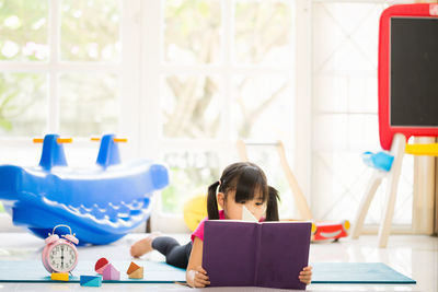 Rear view of girl sitting on table
