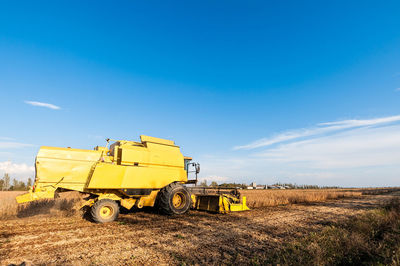 Agricultural machinery on field against blue sky