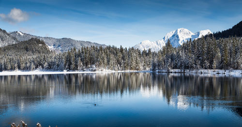 Scenic view of lake by snowcapped mountains against sky