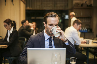 Male entrepreneur working on laptop while drinking coffee in restaurant